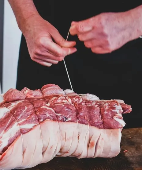 Il macellaio lega a mano un arrosto