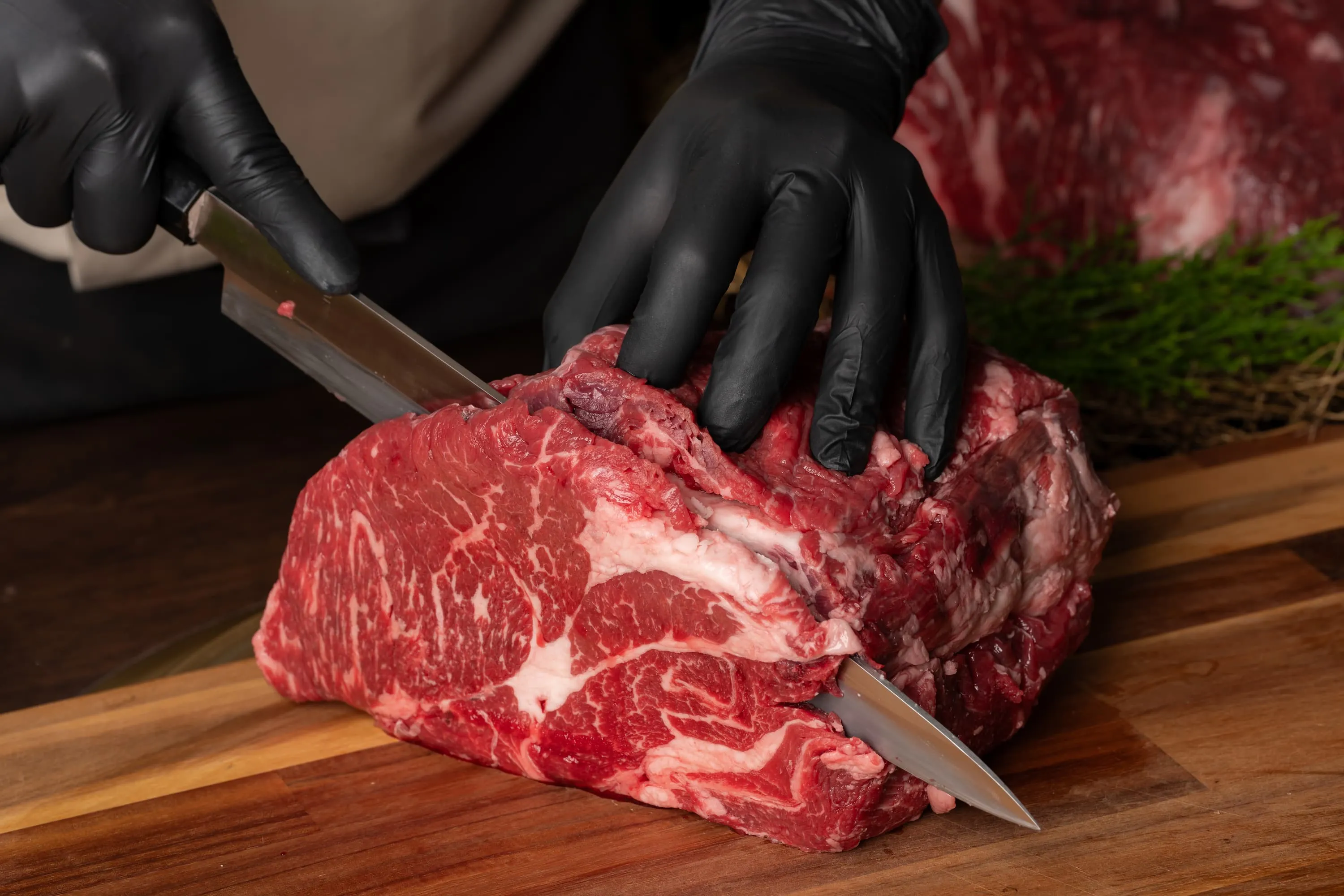 Il macellaio taglia un pezzo di carne marezzata al banco